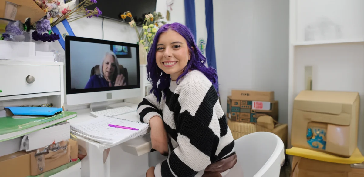 Woman smiling at the camera while on the computer